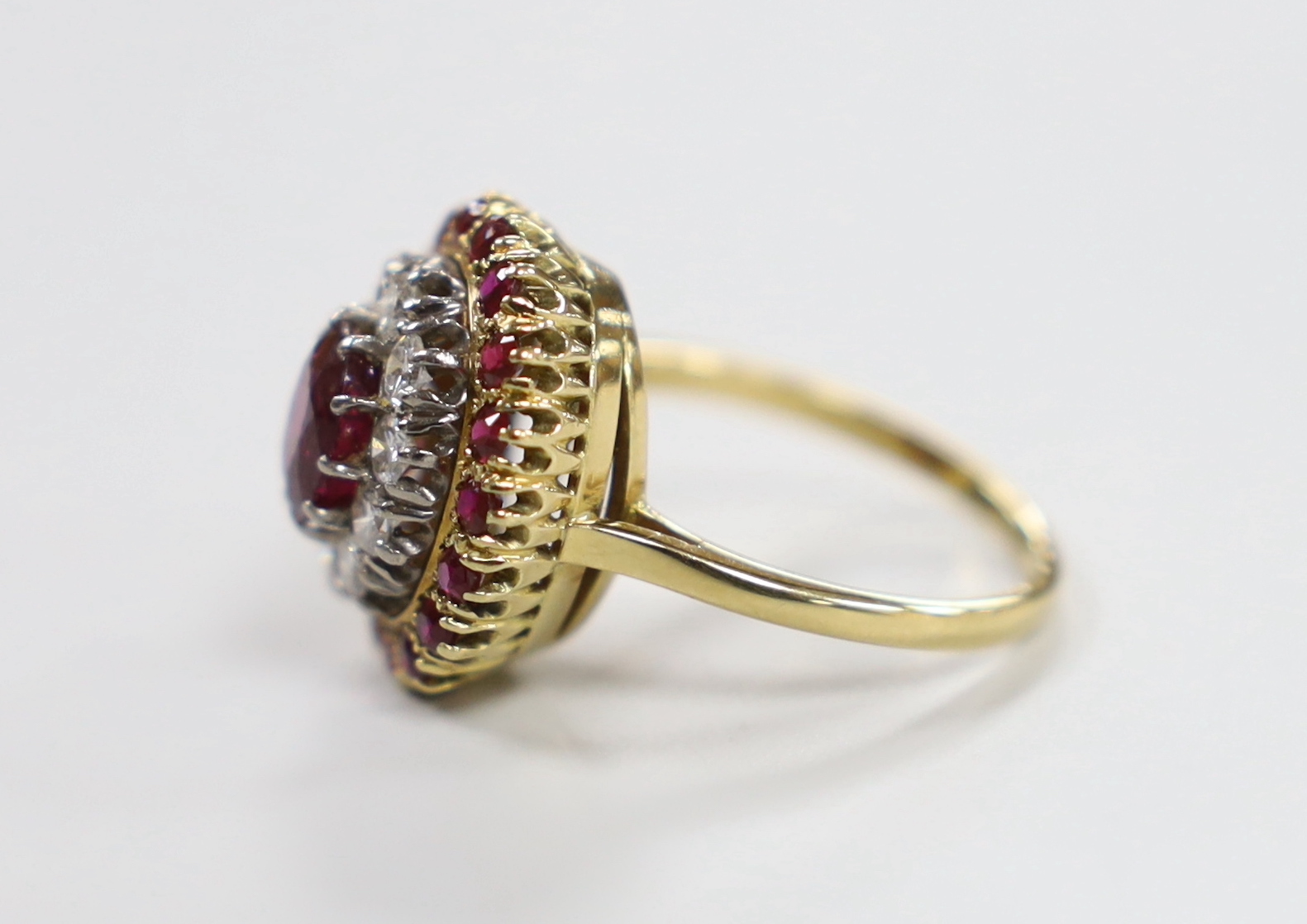 An 18ct, ruby and diamond cluster set oval cluster dress ring, size N/O, gross weight 6.3 grams.